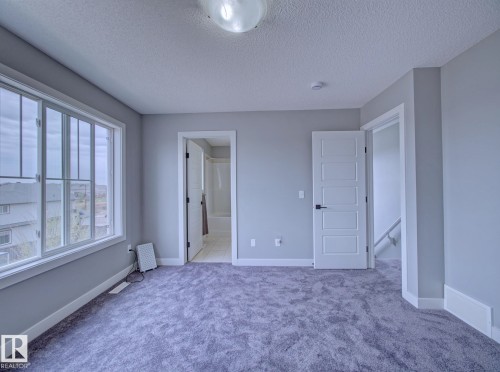 Spacious room featuring plush gray carpeting, a large multipane window, and contemporary white trim - 11 165 Cy Becker Boulevard, Edmonton, AB - Indoor Photo Showing Other Room