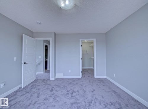 Carpeted room featuring light gray wall paint, white baseboards, and a semi-flush mount ceiling light - 11 165 Cy Becker Boulevard, Edmonton, AB - Indoor