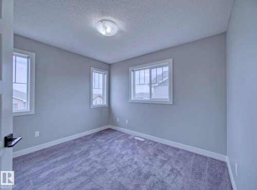 3rd Bedroom Carpeted interior room featuring light gray walls, white trim, and multiple windows - 11 165 Cy Becker Boulevard, Edmonton, AB - Indoor Photo Showing Other Room