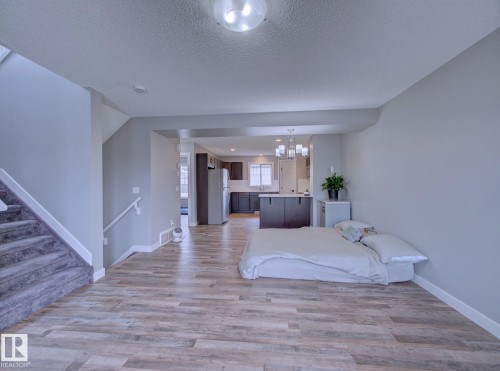 Open-concept living area with wood-finish flooring, a carpeted staircase, and neutral wall tones - 11 165 Cy Becker Boulevard, Edmonton, AB - Indoor