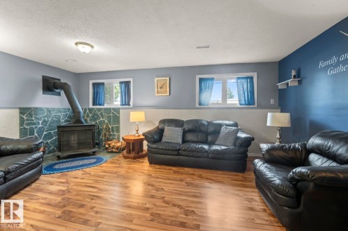 Living area featuring wood-finish flooring and a corner wood stove with a stone surround - 1304 12 Street, Cold Lake, AB - Indoor Photo Showing Living Room With Fireplace