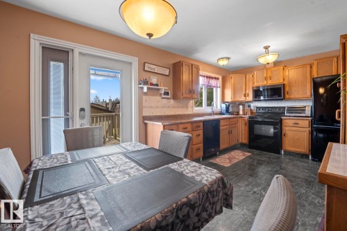 Kitchen featuring wood cabinetry, dark appliances, stone-look countertops, and resilient flooring - 1304 12 Street, Cold Lake, AB - Indoor