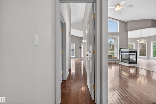 Hardwood flooring throughout, featuring a corner fireplace with a black glass front and white surround - 201 Erin Ridge Drive, St. Albert, AB - Indoor Photo Showing Other Room