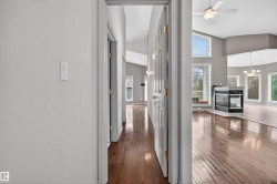 Hardwood flooring throughout, featuring a corner fireplace with a black glass front and white surround - 