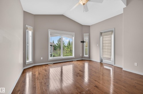 Spacious interior featuring vaulted ceilings, wood-finish flooring, a ceiling fan, multiple windows with roller shades, and a glass-paneled exterior door - 201 Erin Ridge Drive, St. Albert, AB - Indoor Photo Showing Other Room