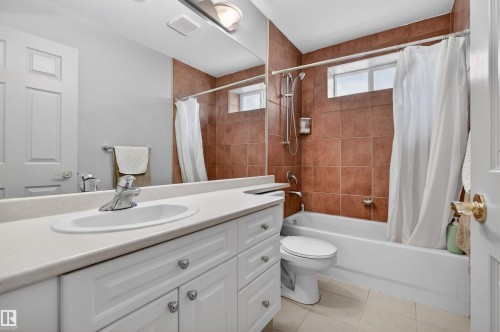 Bathroom featuring a white vanity with integrated sink, a large mirror, a shower-over-tub combination with brown tile surround, and a frosted window - 201 Erin Ridge Drive, St. Albert, AB - Indoor Photo Showing Bathroom
