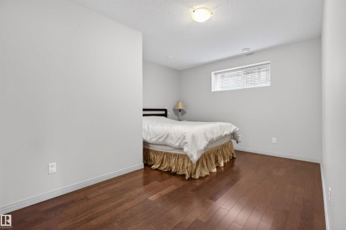 Bedroom featuring wood-finish flooring, white baseboards, a single flush-mount ceiling light, and a rectangular window with horizontal blinds - 201 Erin Ridge Drive, St. Albert, AB - Indoor Photo Showing Bedroom