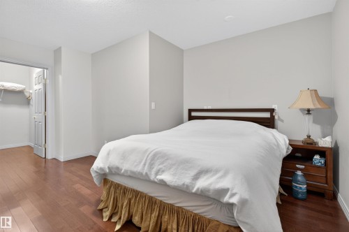 Bedroom featuring wood-finish flooring, light grey painted walls, and a walk-in closet with a bi-fold door and built-in shelving - 201 Erin Ridge Drive, St. Albert, AB - Indoor Photo Showing Bedroom