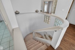 Curved staircase featuring carpeted treads and a painted railing system - 