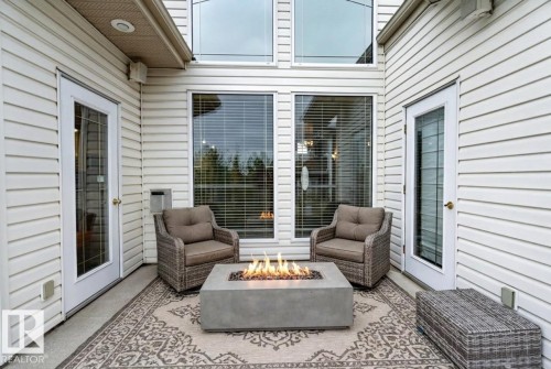 Private patio space featuring a concrete fire pit, white siding, and two glass-paneled exterior doors - 201 Erin Ridge Drive, St. Albert, AB - Outdoor With Deck Patio Veranda With Exterior