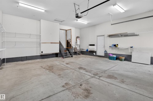 Spacious garage featuring a concrete floor, built-in shelving, two entry doors, and overhead lighting - 201 Erin Ridge Drive, St. Albert, AB - Indoor Photo Showing Garage