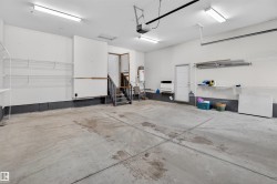 Spacious garage featuring a concrete floor, built-in shelving, two entry doors, and overhead lighting - 