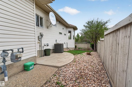 Side yard featuring a concrete patio, gravel landscaping, and a wood fence - 201 Erin Ridge Drive, St. Albert, AB - Outdoor With Exterior