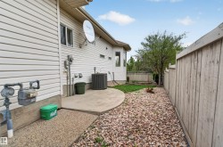 Side yard featuring a concrete patio, gravel landscaping, and a wood fence - 