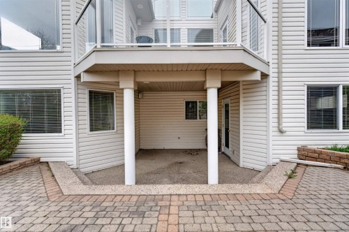 Lower-level covered patio with a textured concrete surface, supported by white columns - 201 Erin Ridge Drive, St. Albert, AB - Outdoor With Exterior