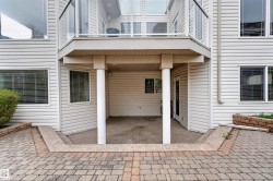 Lower-level covered patio with a textured concrete surface, supported by white columns - 