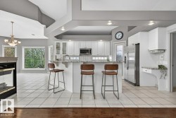Modern kitchen featuring white cabinetry, stainless steel appliances, a granite-finish island with seating, and a tile backsplash - 
