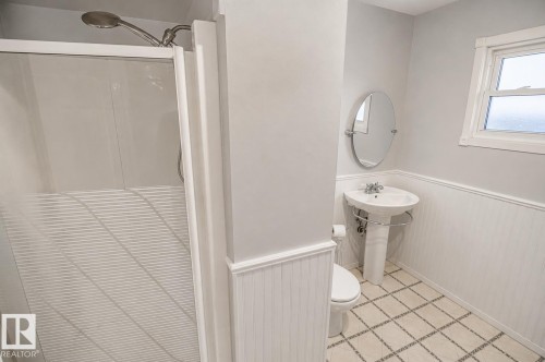 Bathroom featuring a pedestal sink with chrome fixtures, a shower stall with a clear glass enclosure, and a window for natural light - 4510 Lakeshore Dr, St. Paul Town, AB - Indoor Photo Showing Bathroom
