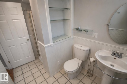 Bathroom featuring a pedestal sink with chrome fixtures, a toilet, a shower enclosure, and built-in shelving with glass shelves - 4510 Lakeshore Dr, St. Paul Town, AB - Indoor Photo Showing Bathroom