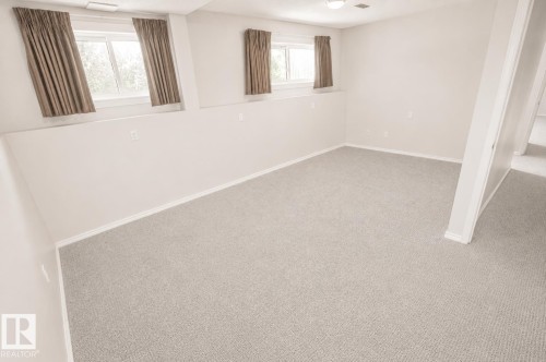 Spacious room featuring light gray carpeting, white painted walls, white trim, and multiple windows with brown curtains - 4510 Lakeshore Dr, St. Paul Town, AB - Indoor Photo Showing Other Room