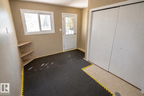 Room featuring neutral wall paint, a single window, an exterior door with glass panels, built-in corner shelving, and bi-fold closet doors - 4510 Lakeshore Dr, St. Paul Town, AB - Indoor Photo Showing Other Room