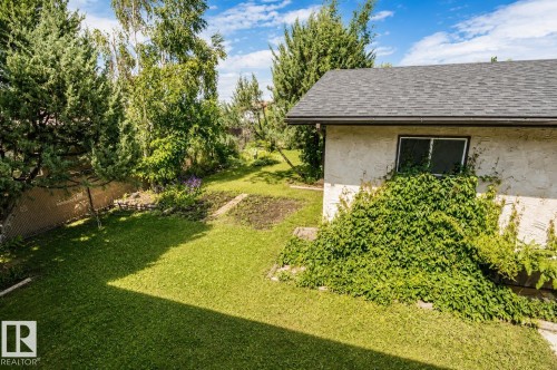 Expansive backyard featuring a lush lawn, mature trees, and a chain-link fence - 4510 Lakeshore Dr, St. Paul Town, AB - Outdoor