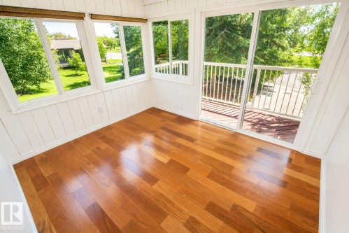 Sun-drenched room featuring polished wood-finish flooring, white paneled walls, multiple large windows, and a sliding glass door opening to a private deck with white railings - 4510 Lakeshore Dr, St. Paul Town, AB -  Photo Showing Other Room