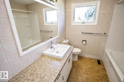 Bathroom featuring a spacious vanity with an integrated sink, polished chrome faucet, and a large wall-mounted mirror - 4510 Lakeshore Dr, St. Paul Town, AB - Indoor Photo Showing Bathroom