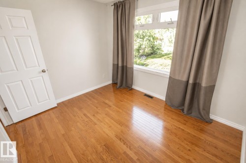 Hardwood flooring throughout featuring white baseboards, a multi-pane window, and a paneled interior door - 4510 Lakeshore Dr, St. Paul Town, AB - Indoor Photo Showing Other Room