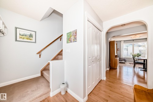 Entryway featuring light wood-finish flooring, white bi-fold closet doors, and an arched doorway leading to an additional room with a large window - 5333 Terwillegar Boulevard, Edmonton, AB - Indoor Photo Showing Other Room