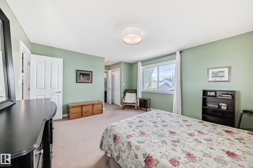 Carpeted room featuring a large window, a ceiling-mounted light fixture, white interior doors, and pale green walls - 5333 Terwillegar Boulevard, Edmonton, AB - Indoor Photo Showing Bedroom