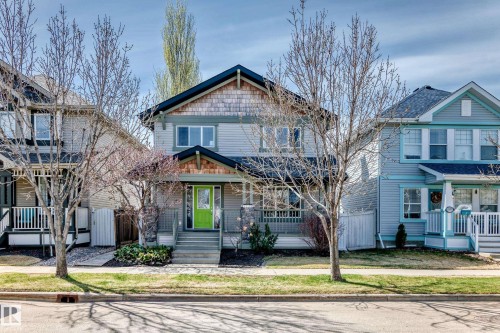 Two-story residence featuring siding and shake exterior elements, a covered front porch, and a vibrant lime green entry door - 5333 Terwillegar Boulevard, Edmonton, AB - Outdoor With Facade