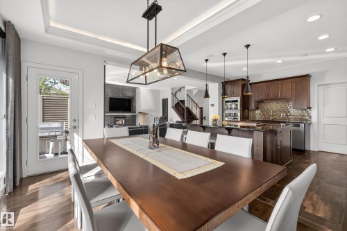 Dining area with wood-finish flooring, featuring a coffered ceiling and a contemporary chandelier - 2760 Watcher Way, Edmonton, AB - Indoor Photo Showing Other Room
