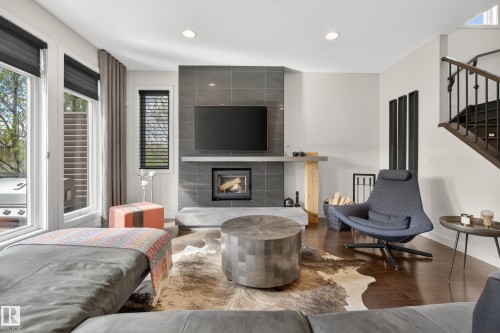 Living area featuring a tiled fireplace surround, integrated fireplace, and wood-finish flooring - 2760 Watcher Way, Edmonton, AB - Indoor Photo Showing Living Room With Fireplace