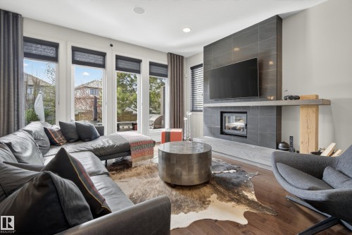 Living area featuring wood-finish flooring and a tiled fireplace surround - 2760 Watcher Way, Edmonton, AB - Indoor Photo Showing Living Room With Fireplace