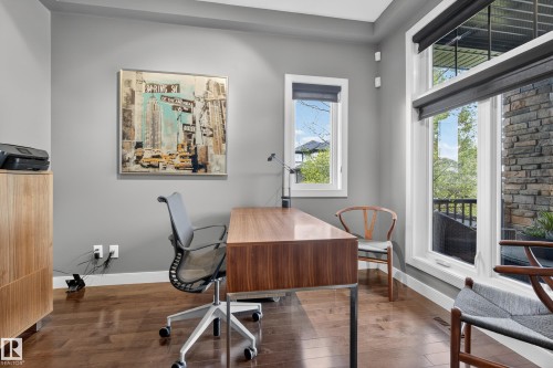 Hardwood-finish flooring, light grey wall paint, and white trim complement the large windows featuring dark roller shades - 2760 Watcher Way, Edmonton, AB - Indoor Photo Showing Office