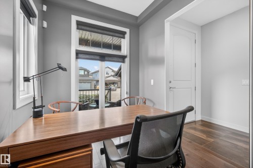 Dedicated room featuring engineered wood flooring, a window wall with roller shades, and direct outdoor access - 2760 Watcher Way, Edmonton, AB - Indoor