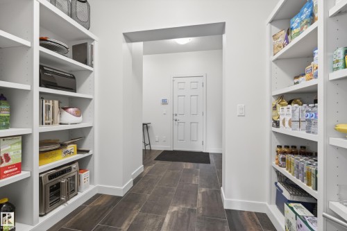 Spacious pantry featuring extensive built-in shelving, durable tile flooring, and a wide entryway - 2760 Watcher Way, Edmonton, AB - Indoor