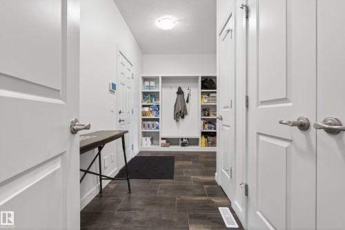 Entryway featuring dark tile flooring, white walls, built-in storage cubbies, and multiple white paneled doors - 2760 Watcher Way, Edmonton, AB - Indoor Photo Showing Other Room