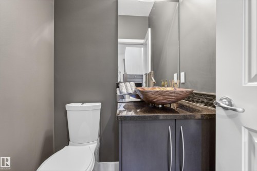 Contemporary powder room featuring a vessel sink, dark stone countertop, and custom vanity cabinetry - 2760 Watcher Way, Edmonton, AB - Indoor Photo Showing Bathroom
