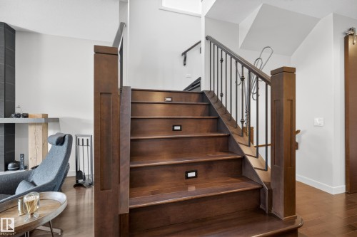 Hardwood staircase featuring integrated step lighting and decorative metal balusters - 2760 Watcher Way, Edmonton, AB - Indoor Photo Showing Other Room