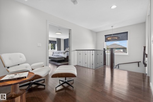 Hardwood flooring extending throughout an upper-level hallway, featuring recessed lighting and a window with a chandelier - 2760 Watcher Way, Edmonton, AB - Indoor Photo Showing Other Room