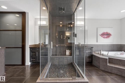 Glass-enclosed shower with pebble-tile floor and recessed shelf - 2760 Watcher Way, Edmonton, AB - Indoor Photo Showing Bathroom