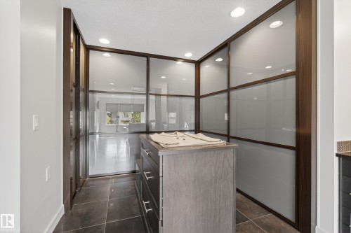 Custom closet system featuring dark wood-finish framing and frosted glass panels - 2760 Watcher Way, Edmonton, AB - Indoor Photo Showing Other Room