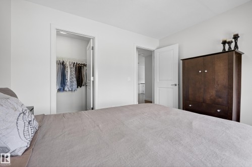 White interior with an open closet featuring hanging storage, a two-panel interior door, and light-colored walls - 2760 Watcher Way, Edmonton, AB - Indoor Photo Showing Bedroom