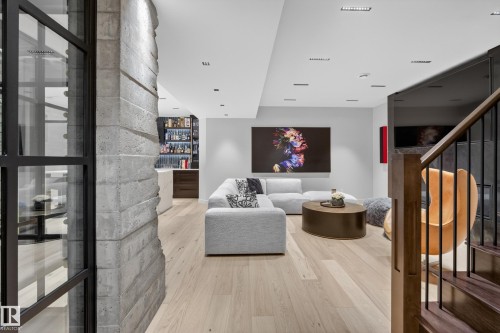 Open-concept living space featuring wood-finish flooring, recessed lighting, and a built-in wet bar with dark wood cabinetry and a light-toned countertop - 2760 Watcher Way, Edmonton, AB - Indoor