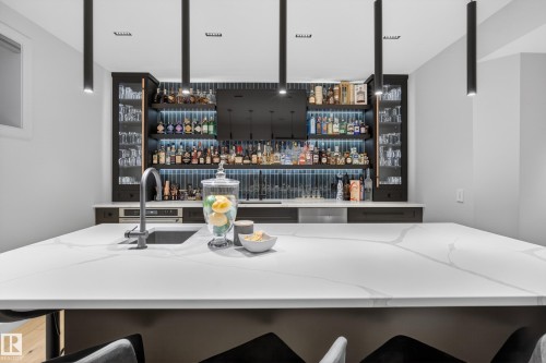 Contemporary wet bar featuring a large white countertop with veining, an undermount sink, and a gooseneck faucet - 2760 Watcher Way, Edmonton, AB - Indoor Photo Showing Kitchen