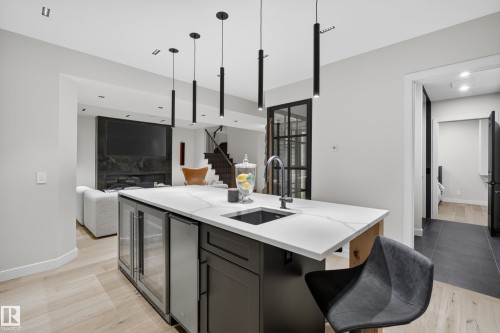 Kitchen island with a white countertop and integrated sink, featuring built-in beverage refrigerators - 2760 Watcher Way, Edmonton, AB - Indoor Photo Showing Kitchen With Upgraded Kitchen