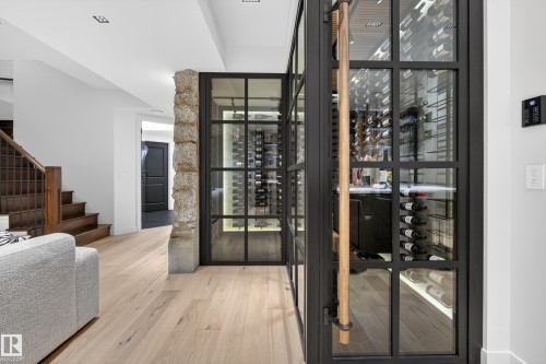 Custom wine cellar featuring industrial-style glass and steel doors and interior lighting - 2760 Watcher Way, Edmonton, AB - Indoor Photo Showing Other Room
