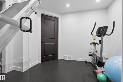 Dedicated fitness area featuring durable black flooring, recessed lighting, and a modern two-panel interior door - 2760 Watcher Way, Edmonton, AB - Indoor Photo Showing Gym Room